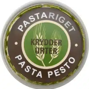 Rundt låg med grøn/brun design, urter illustrationer. Tekst: "PASTARIGET KRYDDERURTER PASTA PESTO".