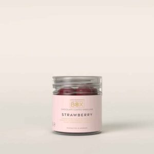 Klar beholder med lyserødt mærkat, der viser røde, runde slik. Teksten "STRAWBERRY" er synlig.